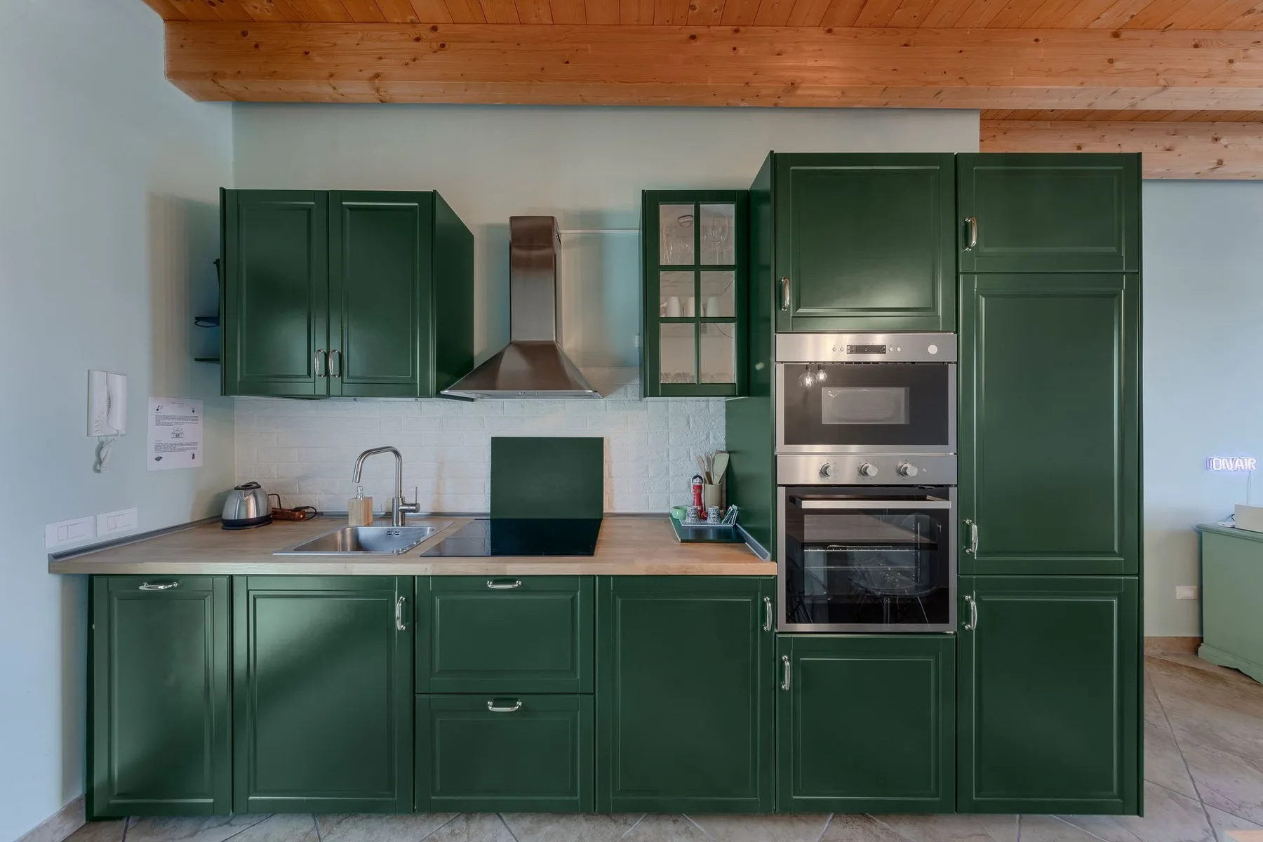 Una cocina con gabinetes verde oscuro, una encimera y electrodomésticos integrados.