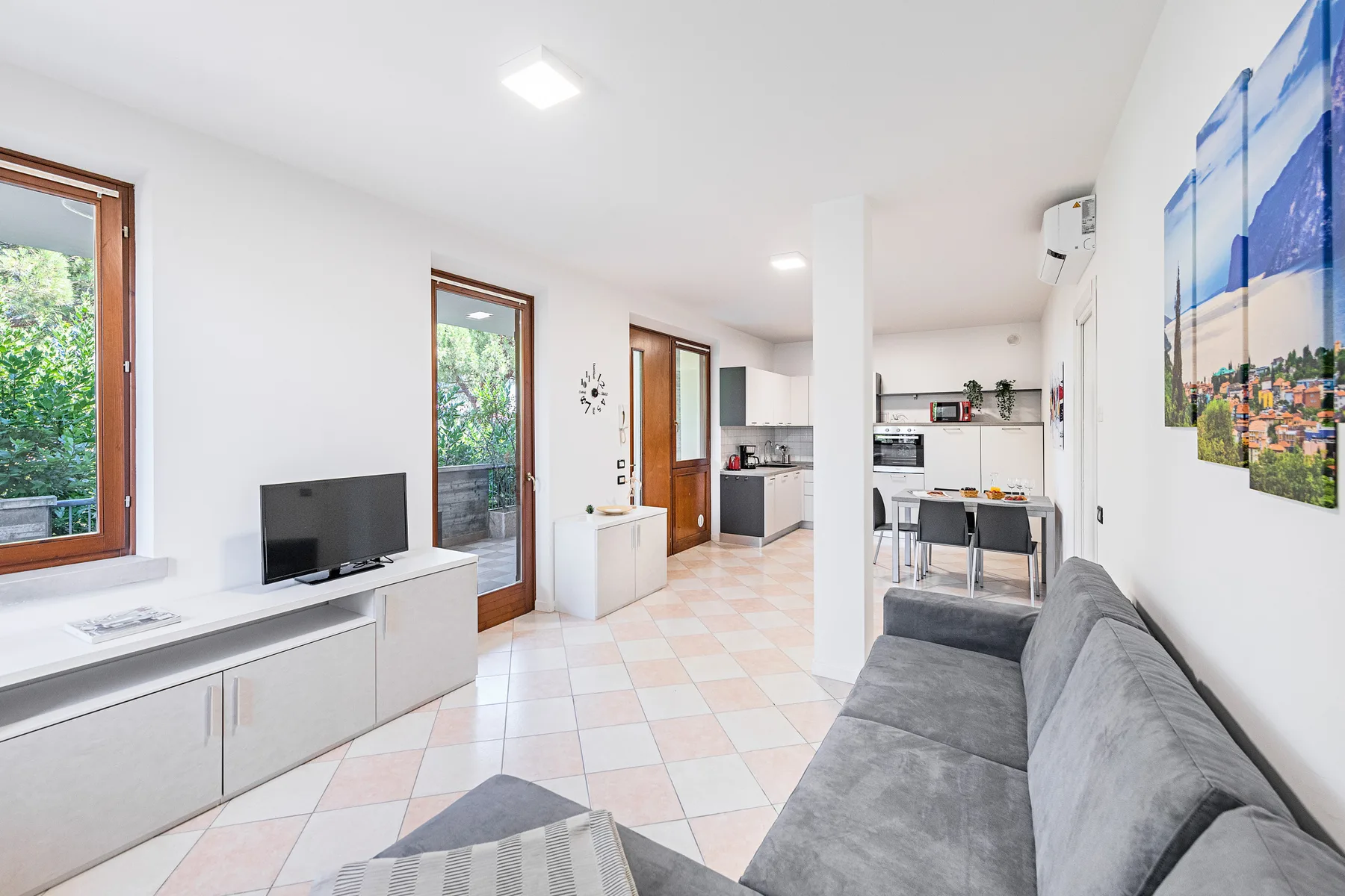 Una sala luminosa con asientos grises y una cocina abierta.