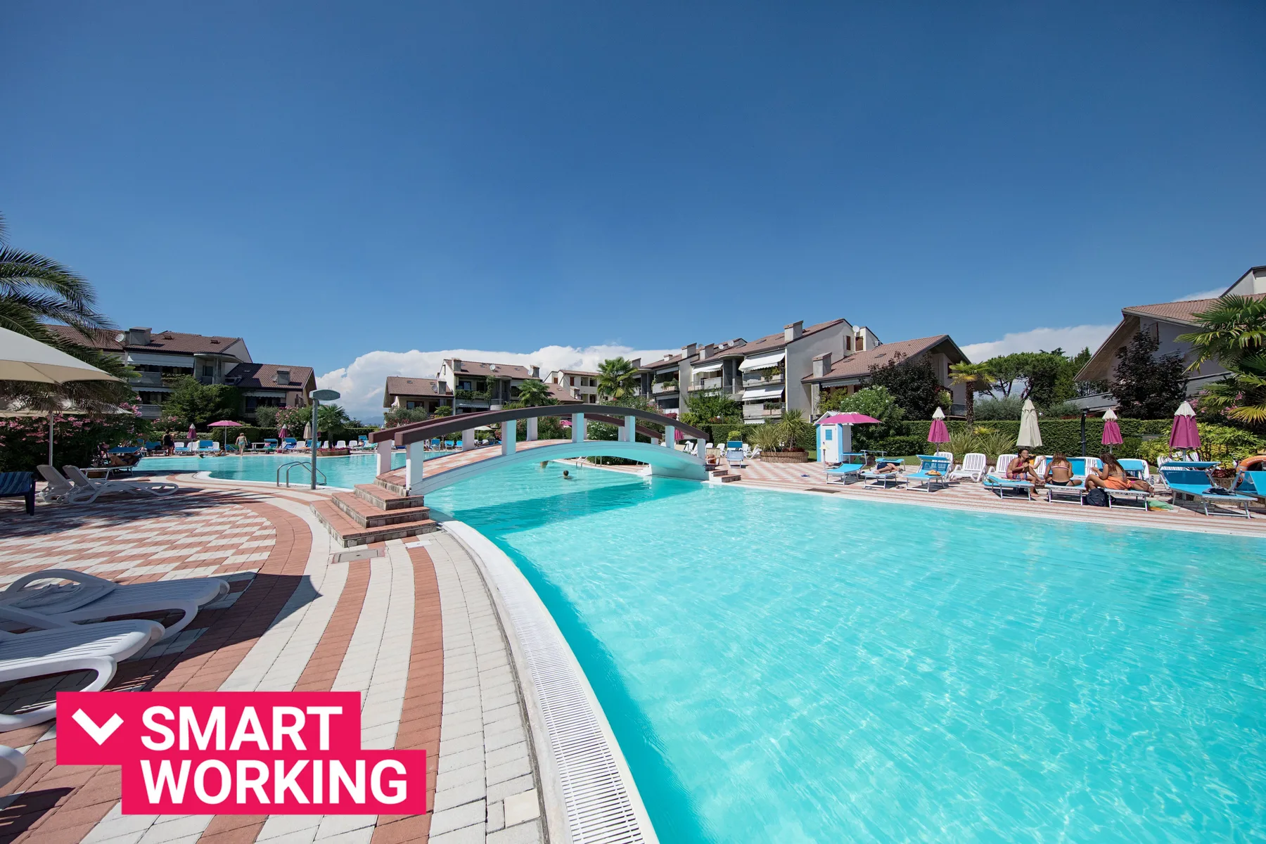 Una piscina al aire libre con un puente curvo y asientos alrededor de la terraza.