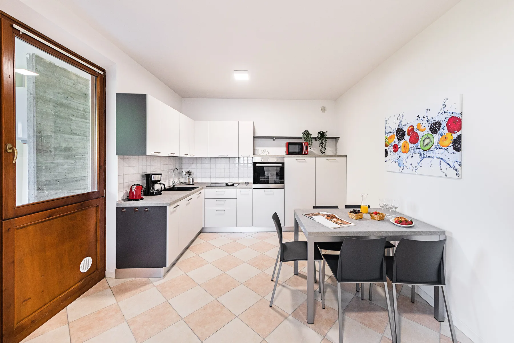 Una cocina y comedor luminosos con gabinetes blancos y una mesa.