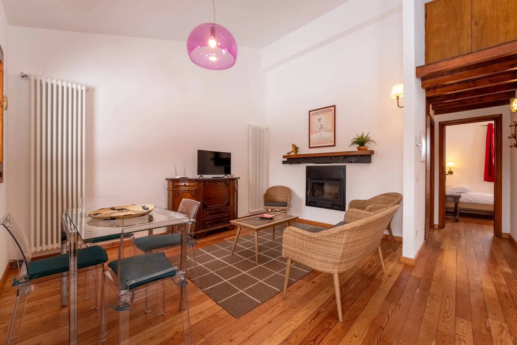 A living room with seating arranged around a fireplace and a dining table.