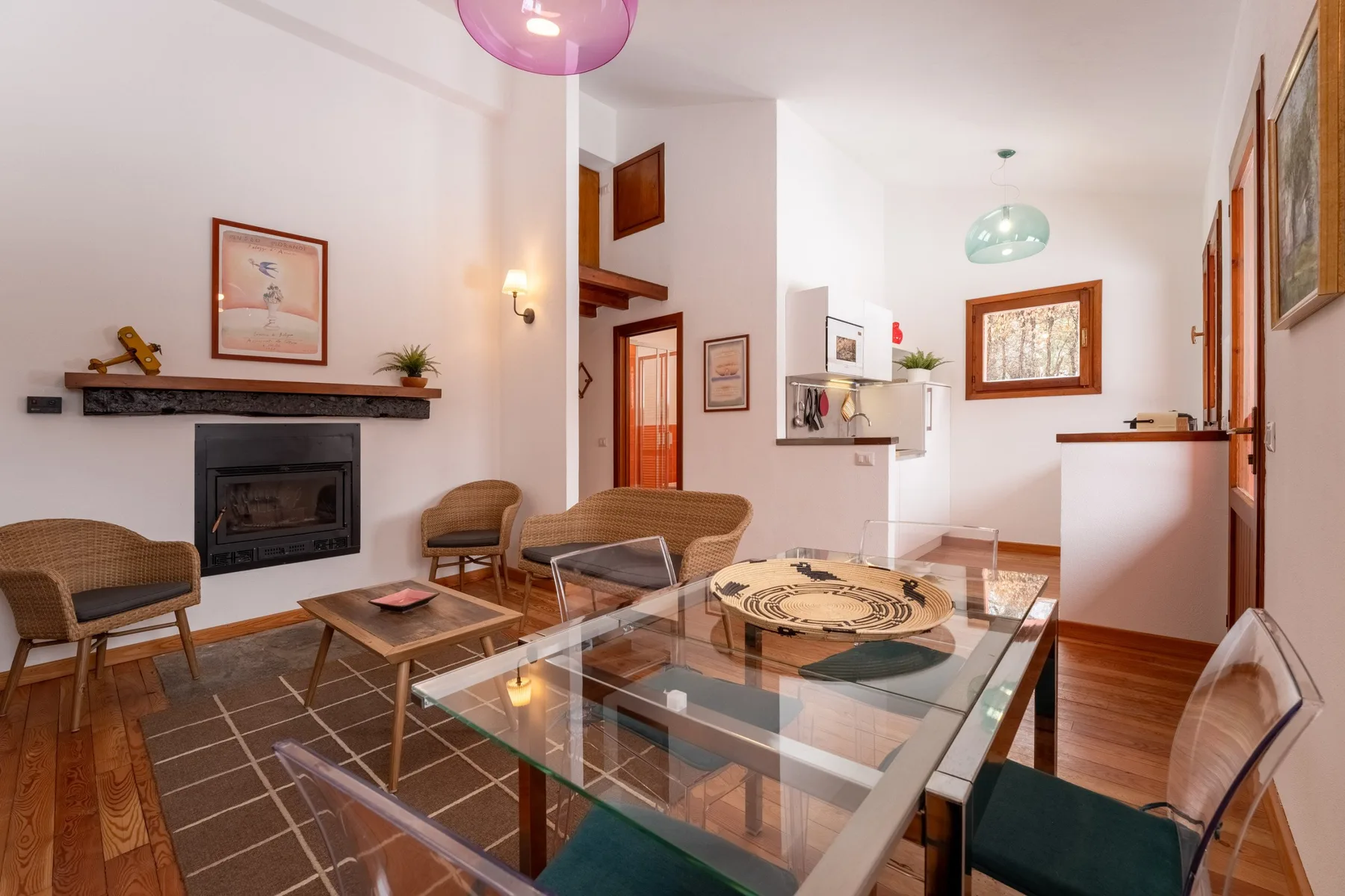 A living and dining area with seating around a glass table and a fireplace.