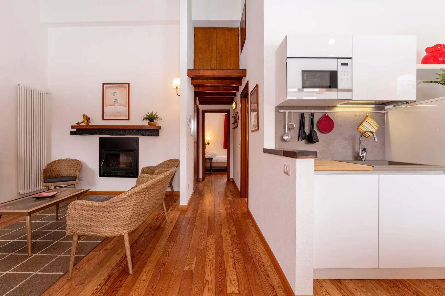 A bright open-plan living room and kitchen with a fireplace and wooden floors.