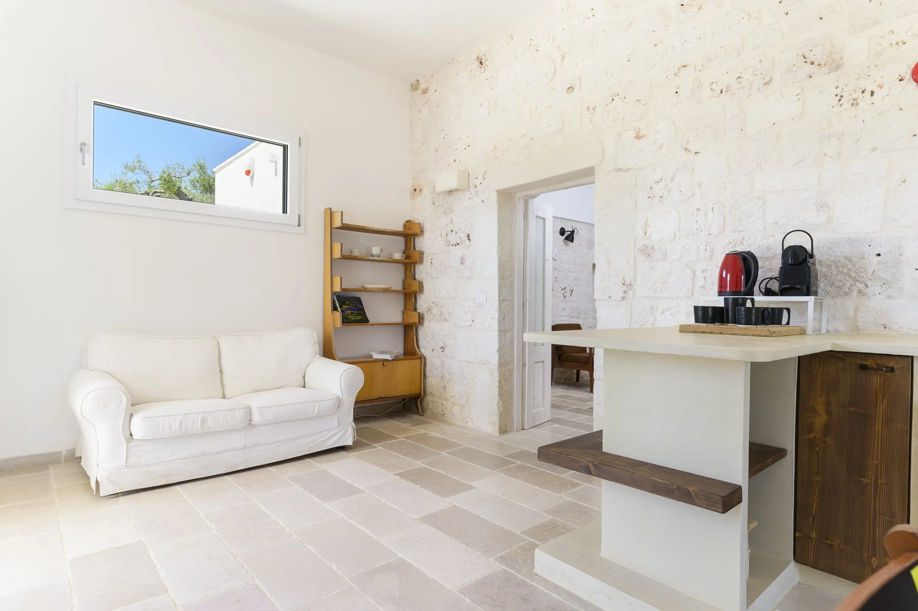 Una luminosa sala de estar con un sofá blanco y una barra de cocina abierta.