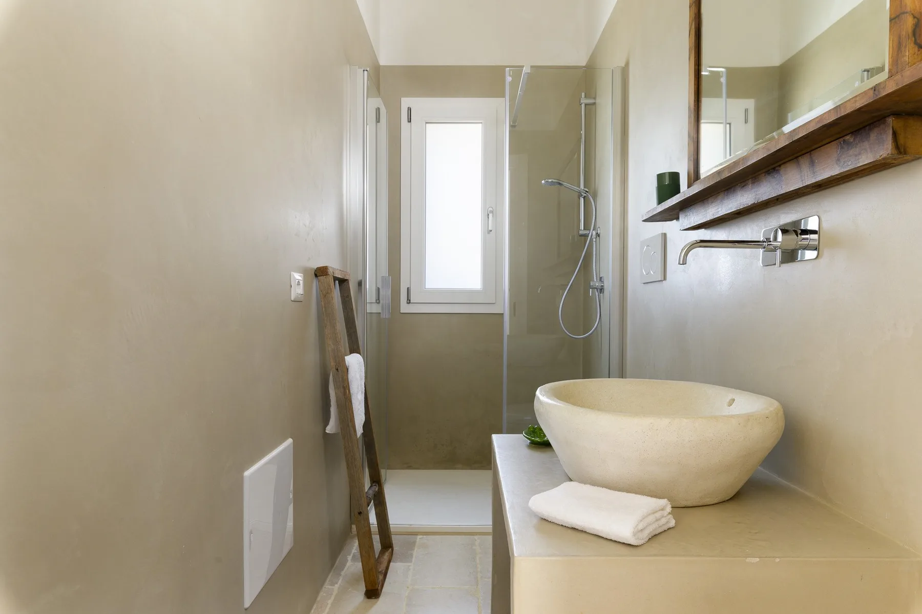 Un baño con lavabo sobre encimera, espejo de pared y ducha.
