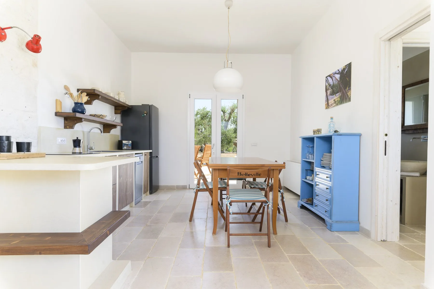 Un comedor luminoso con una mesa de madera junto a una cocina compacta.