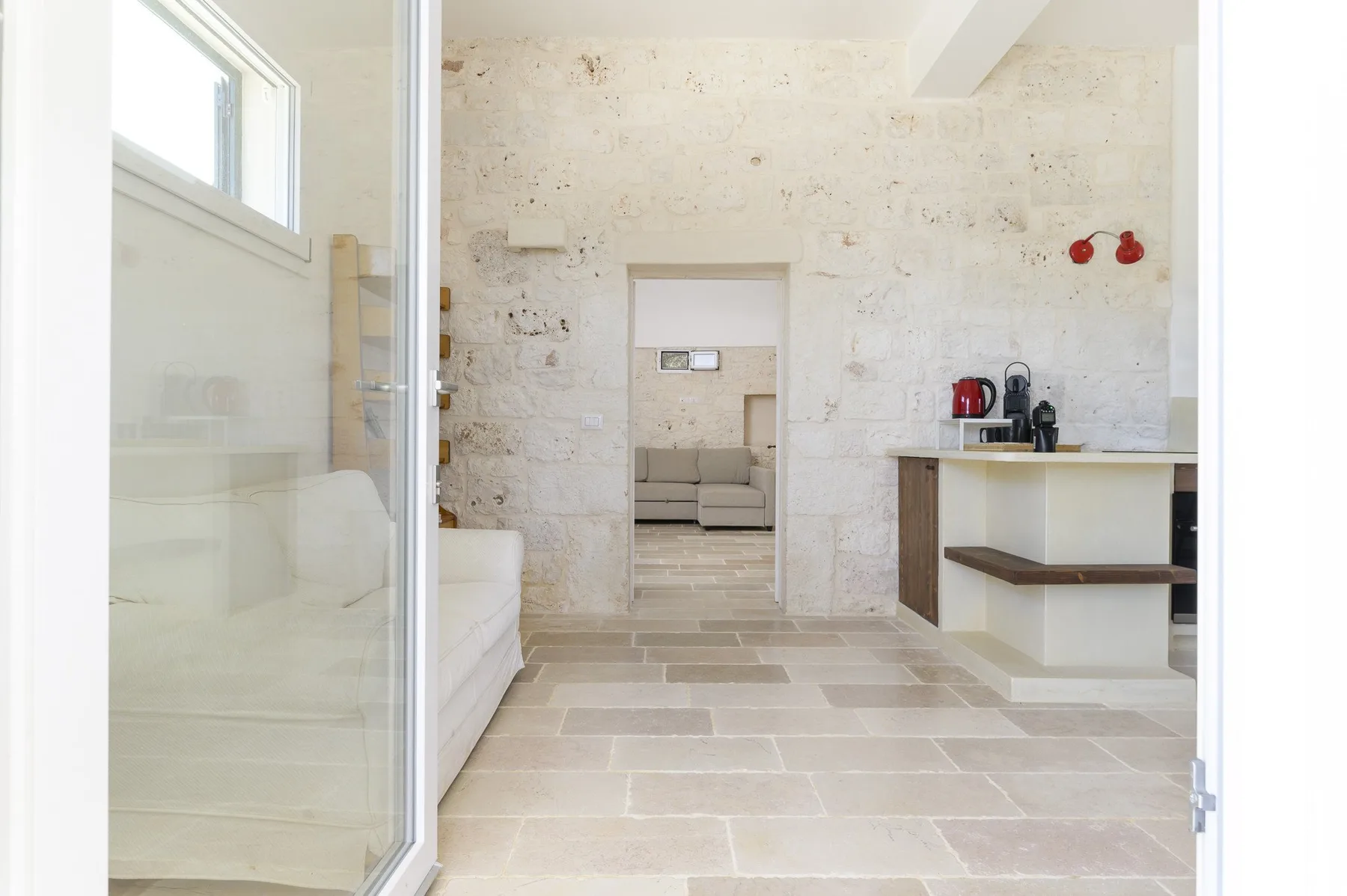 Un interior luminoso de piedra con asientos visibles a través de una puerta abierta.