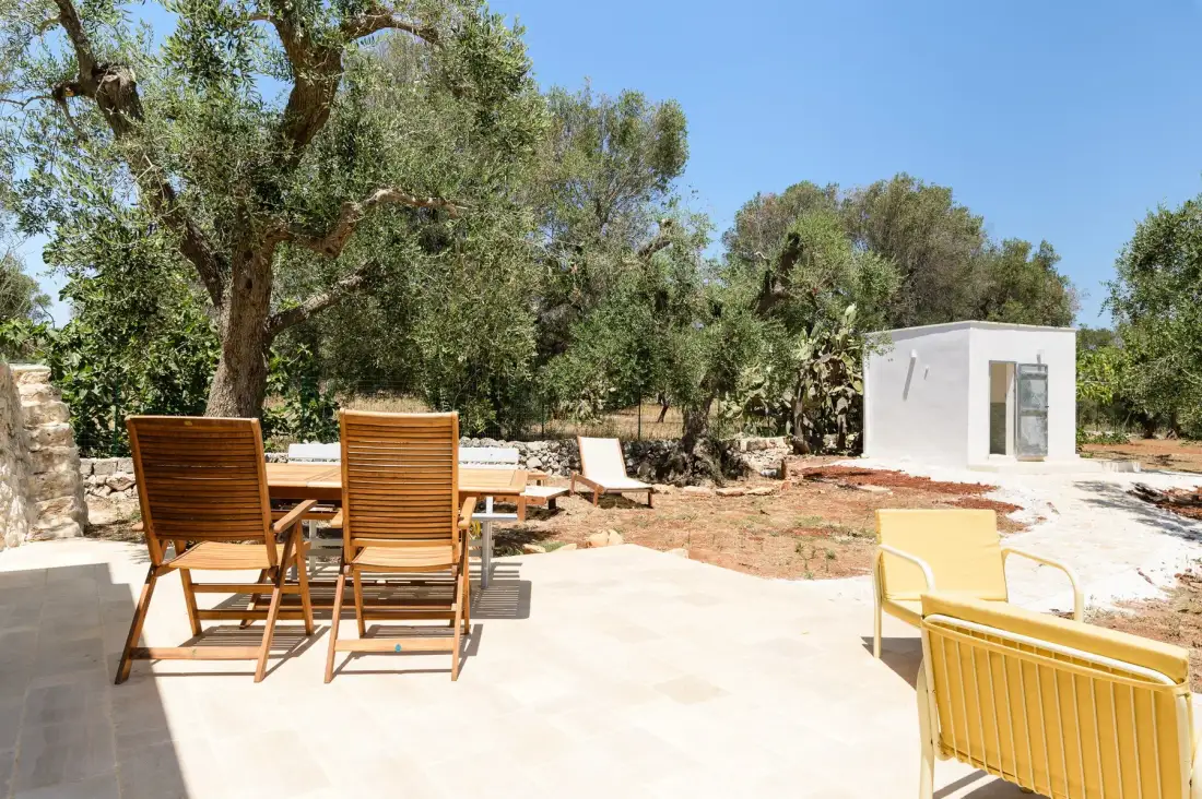 Un patio exterior con asientos de madera y una pequeña construcción blanca.