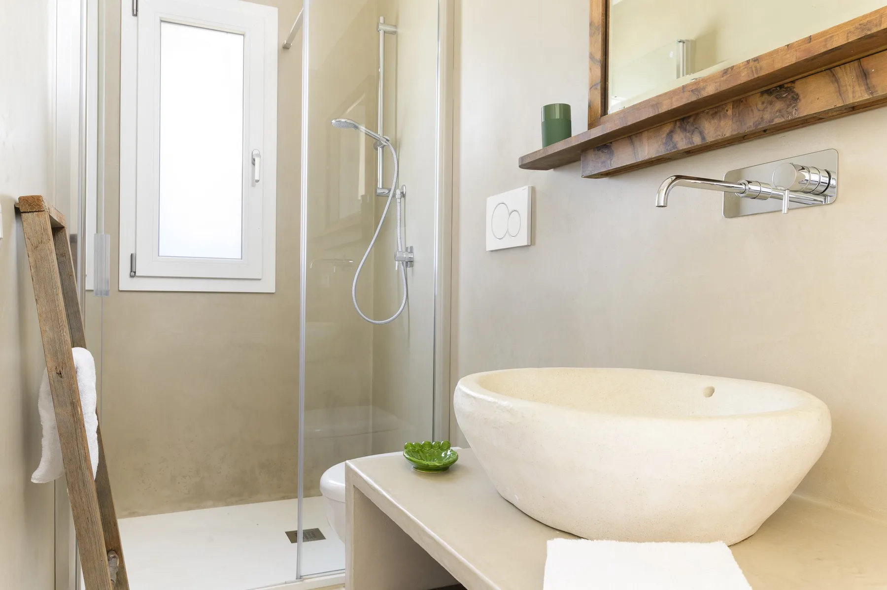 Un baño con un lavabo blanco sobre encimera junto a una ducha de vidrio.