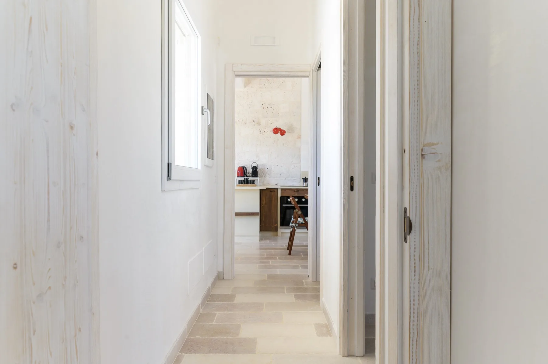 Un pasillo luminoso conduce a una cocina, con una ventana junto a la pared.