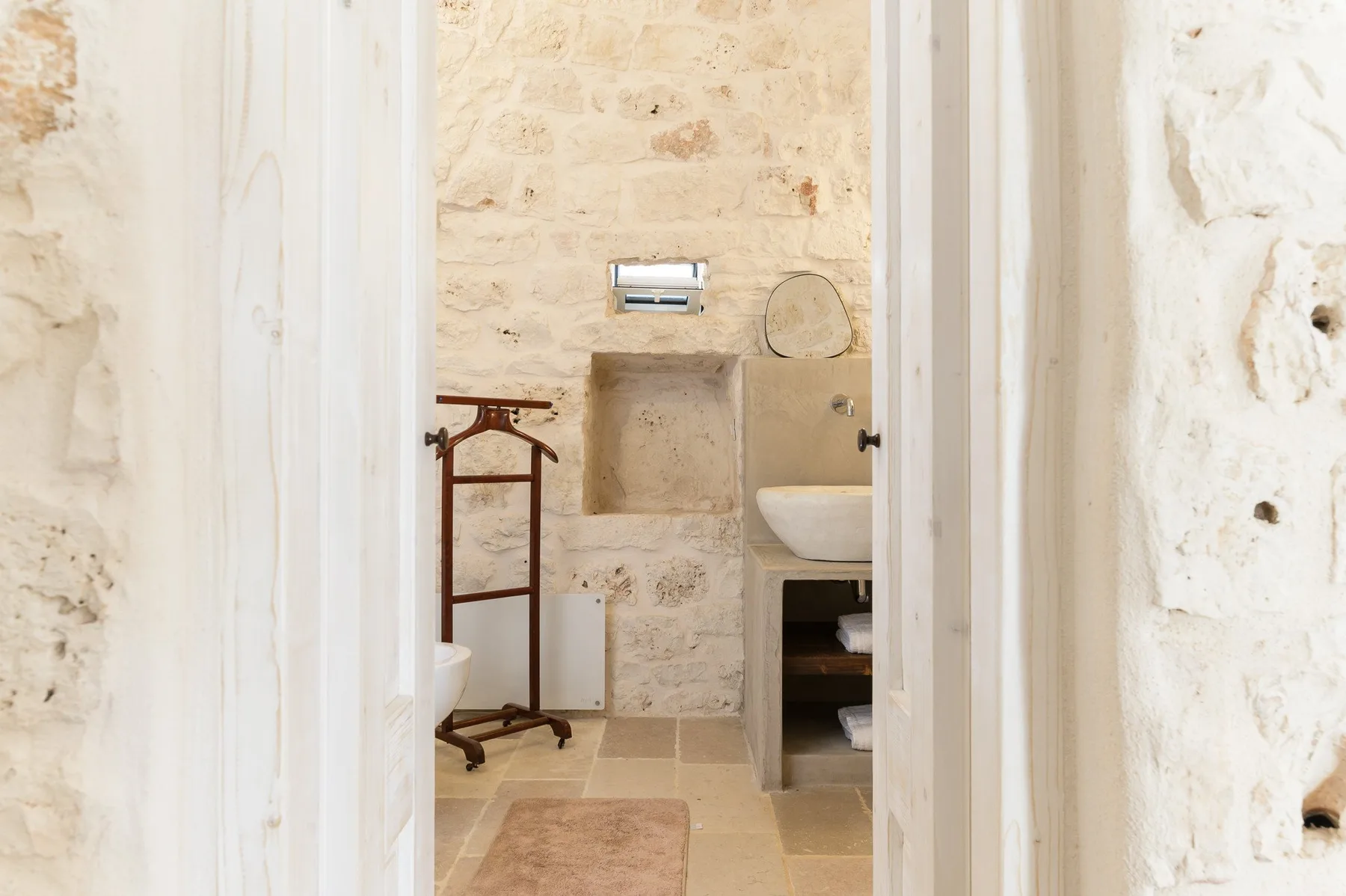 Un baño con lavabo, nicho empotrado en la pared y paredes de piedra.