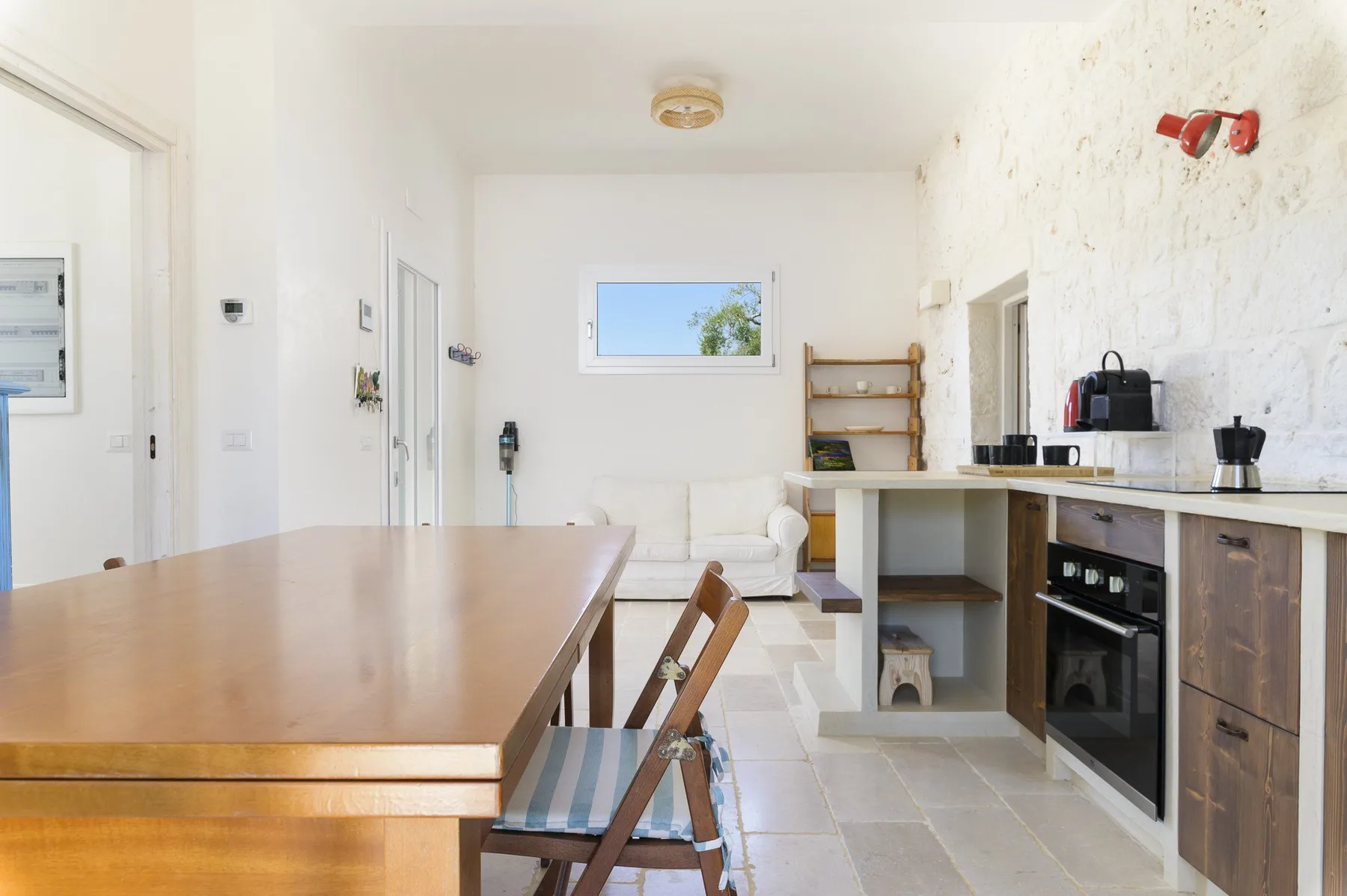 Una cocina y comedor luminosos con una mesa de madera y una encimera.