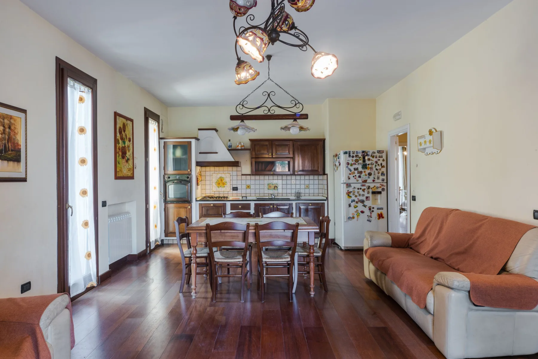 Comedor con mesa y sillas de madera junto a una cocina.