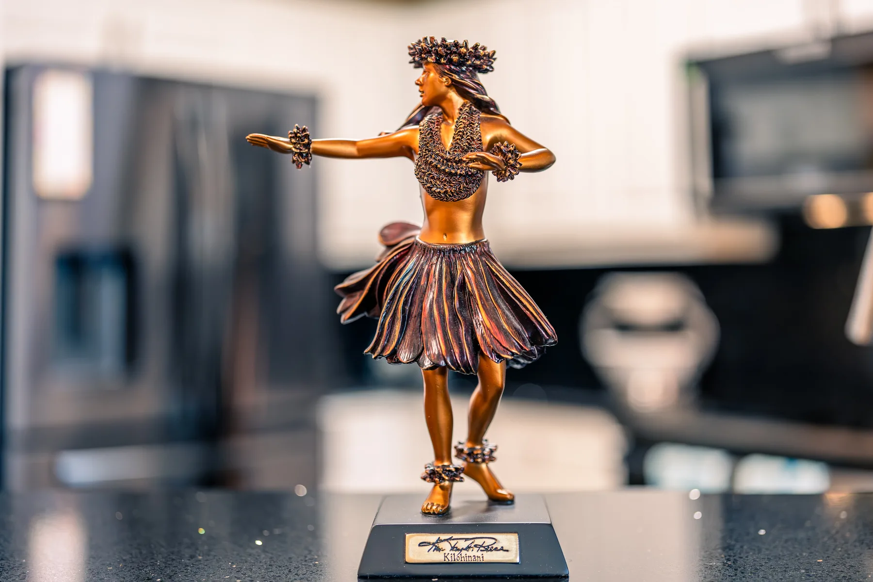 Una pequeña figura de una bailarina está sobre una base de exhibición en una habitación.