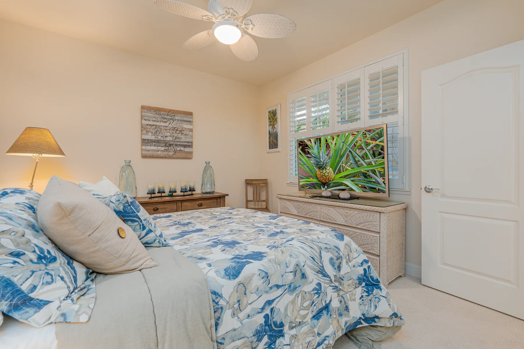 Un dormitorio con una cama cubierta de ropa de cama floral azul y una ventana con persianas.