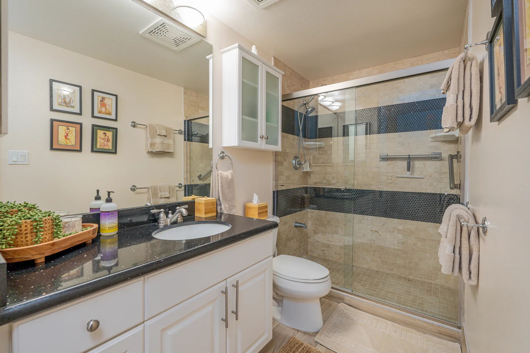Un baño con un tocador largo y una ducha con mampara de vidrio.