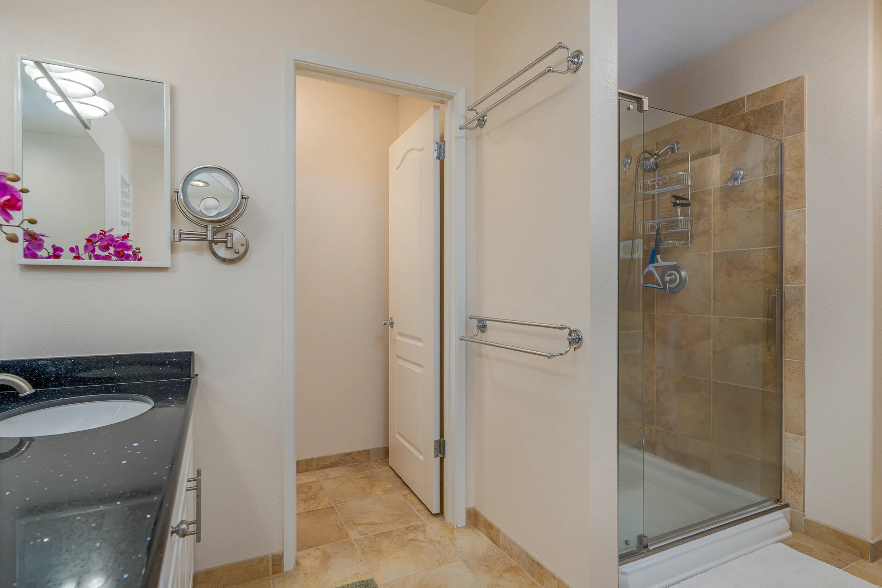 Un baño con lavabo, espejo de pared y ducha de vidrio.