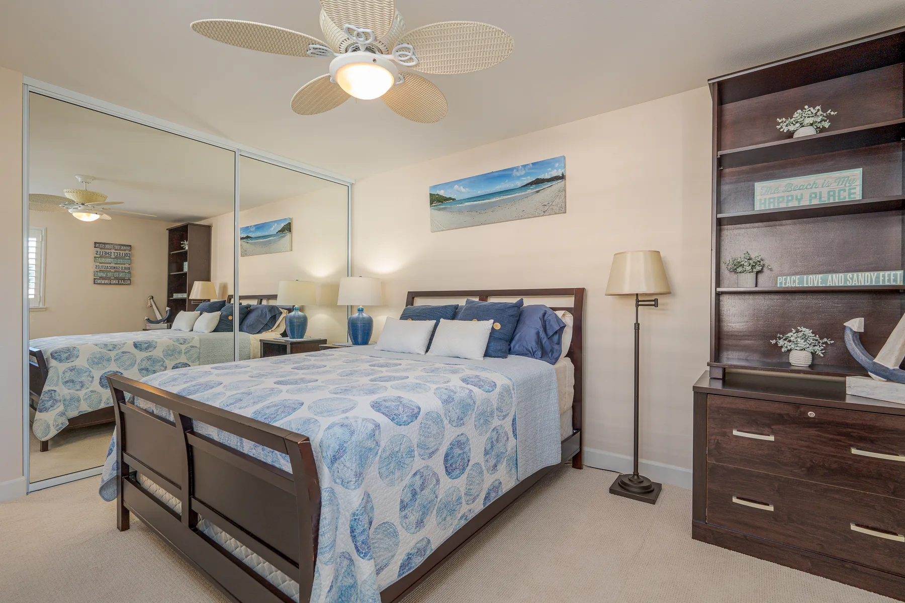 Dormitorio con una cama vestida con ropa de cama estampada en azul y blanco y puertas de armario con espejo.
