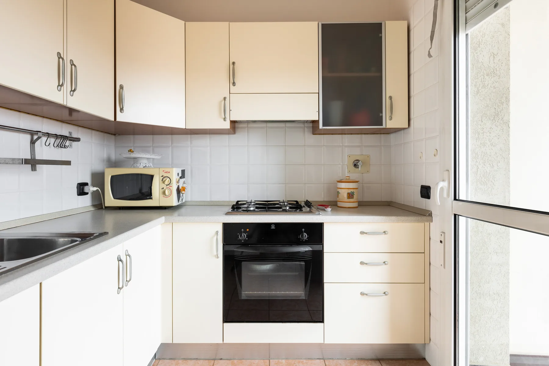 Una cocina luminosa con gabinetes blancos, una estufa y una ventana amplia.