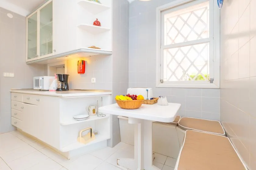 A bright kitchen with a countertop and a small dining table beside the window.