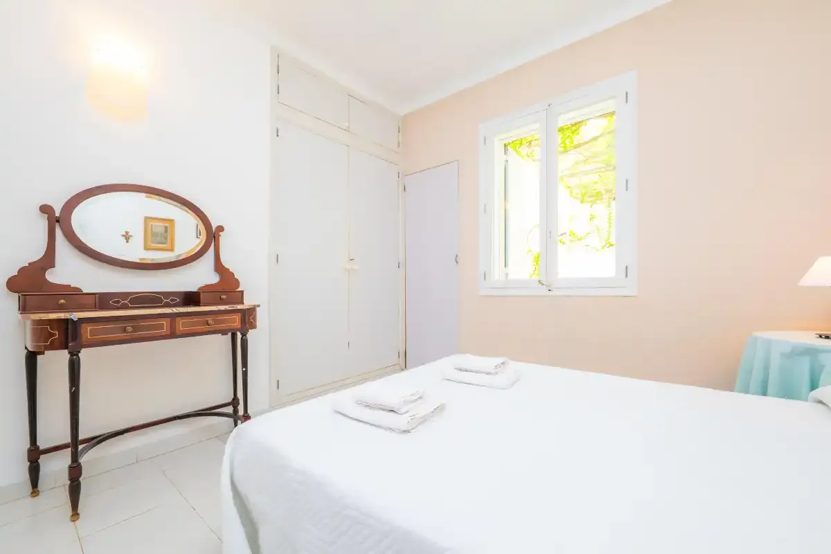 A bright bedroom with a neatly made bed and a window.
