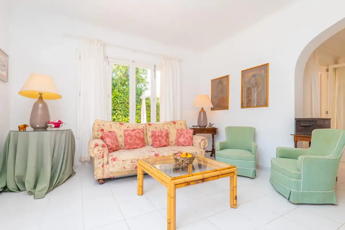 A bright living room with a floral sofa and a glass-topped coffee table.