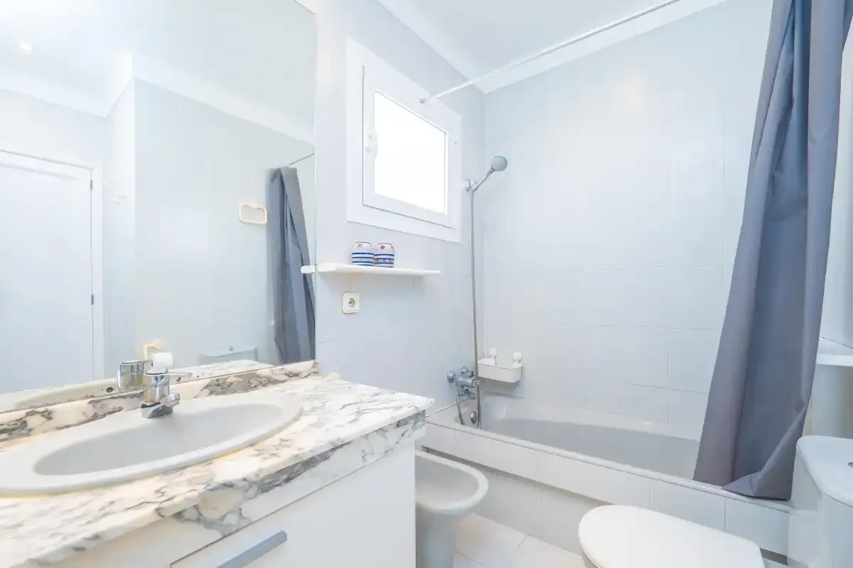 A bright bathroom with a bathtub, shower, and sink.