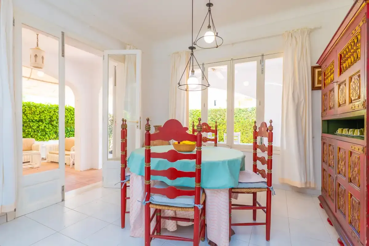 A dining area with a turquoise tablecloth and red wooden chairs.
