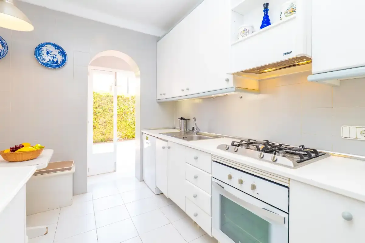 A bright white kitchen with a gas cooktop and an arched doorway.