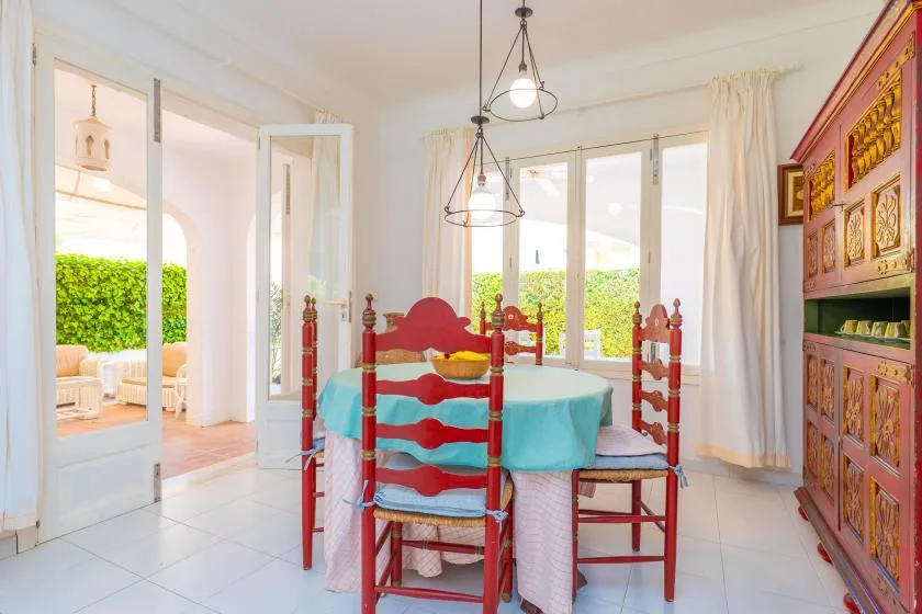 A dining area with a table and red wooden seating beside large windows.