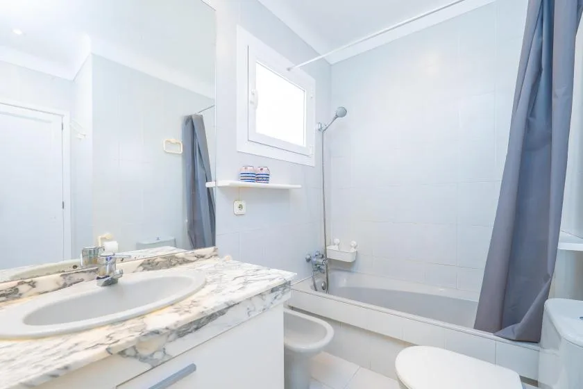 A bright bathroom with a sink vanity and bathtub behind a shower curtain.