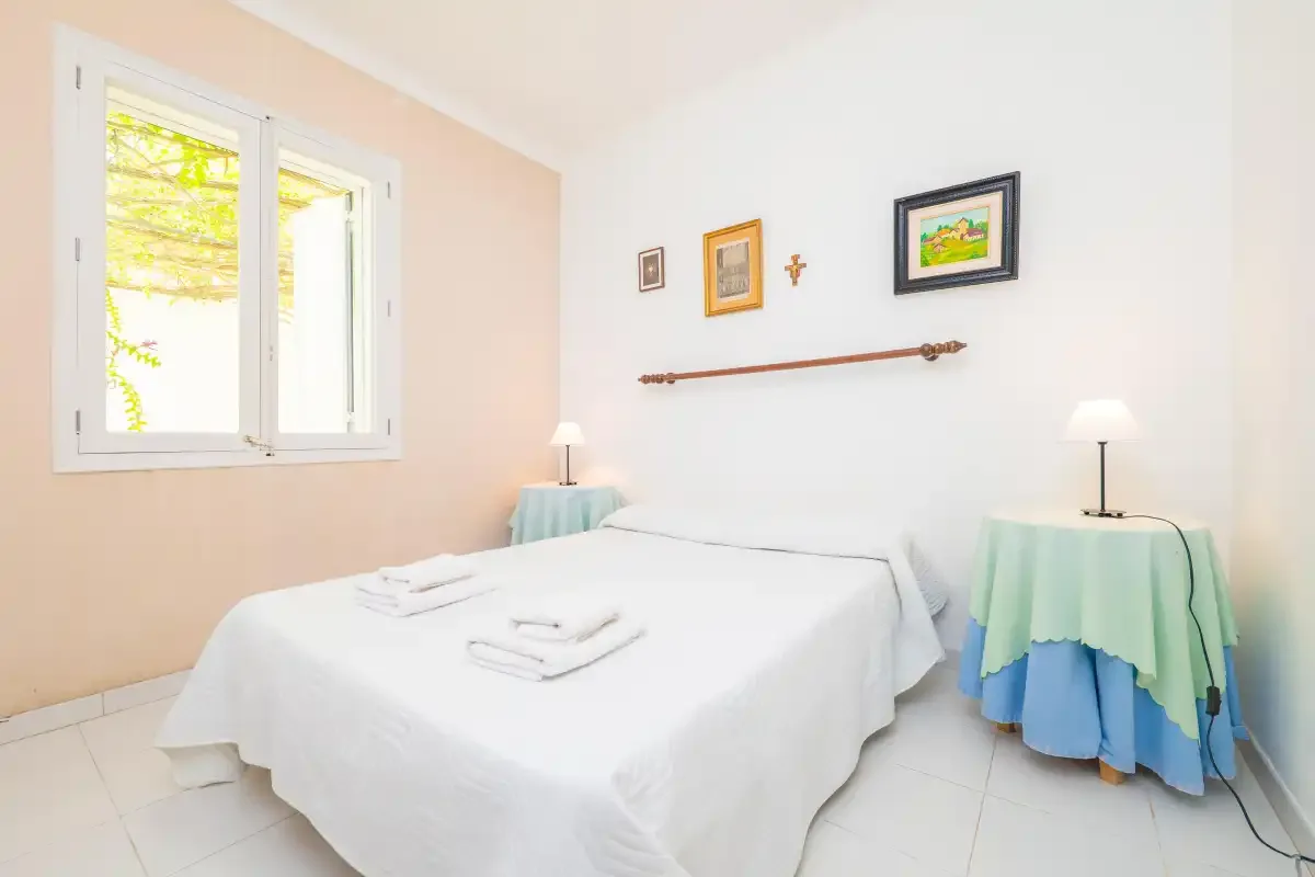 A bedroom with a neatly made bed and framed pictures on the wall.