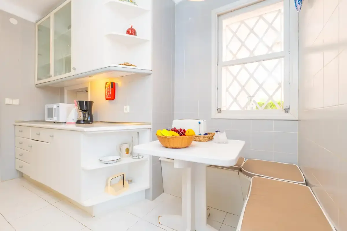A bright kitchen with white cabinets, a countertop, and a small dining table.