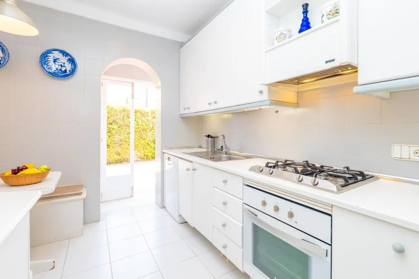A bright white kitchen with cabinets, a countertop, and a gas cooktop.