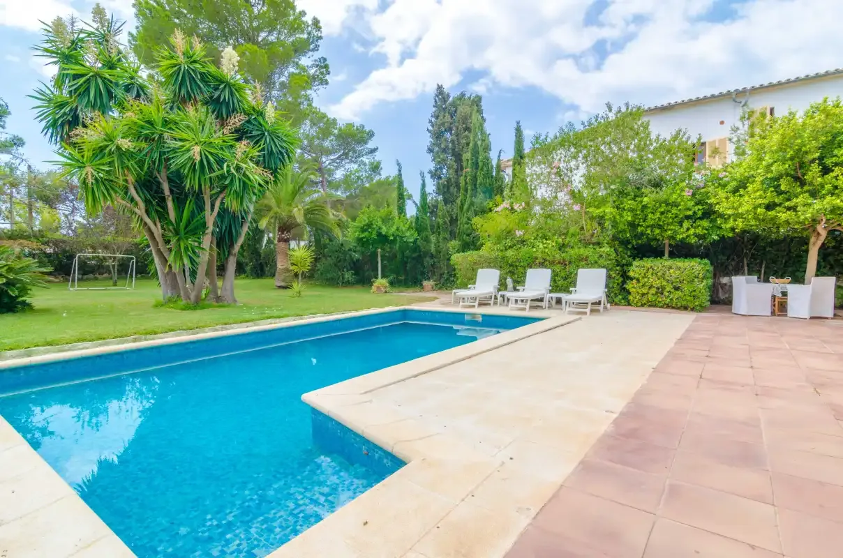 An outdoor pool beside a paved patio and landscaped garden.