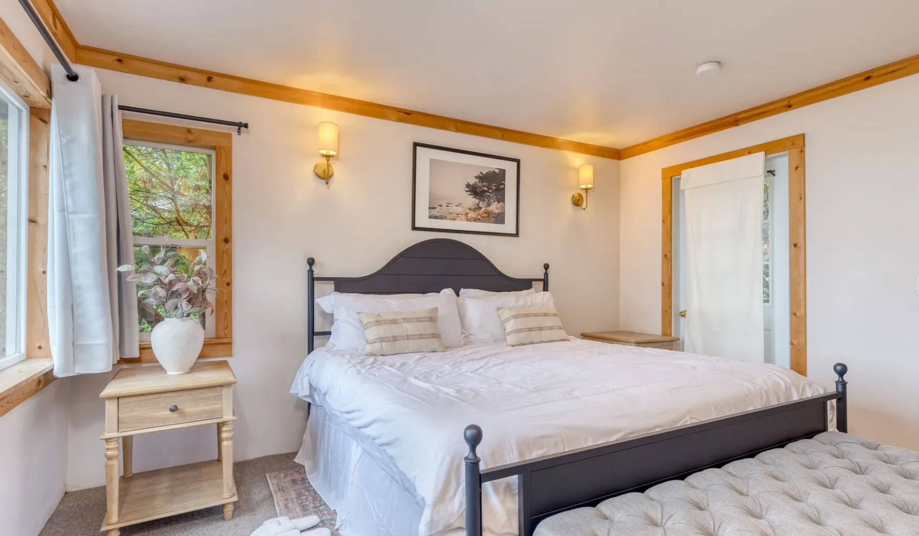 Un dormitorio con una cama grande, una mesita de noche y ventanas.