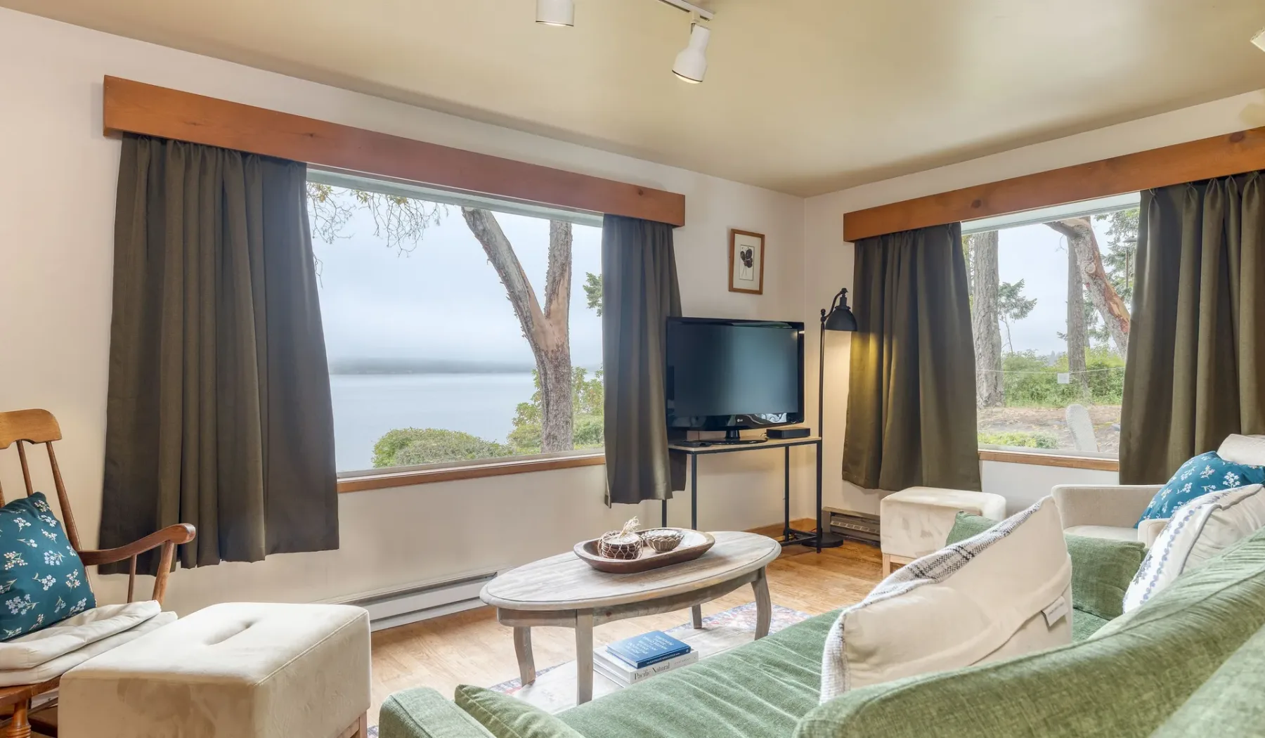 Una sala de estar con asientos y grandes ventanas con vista a un lago.