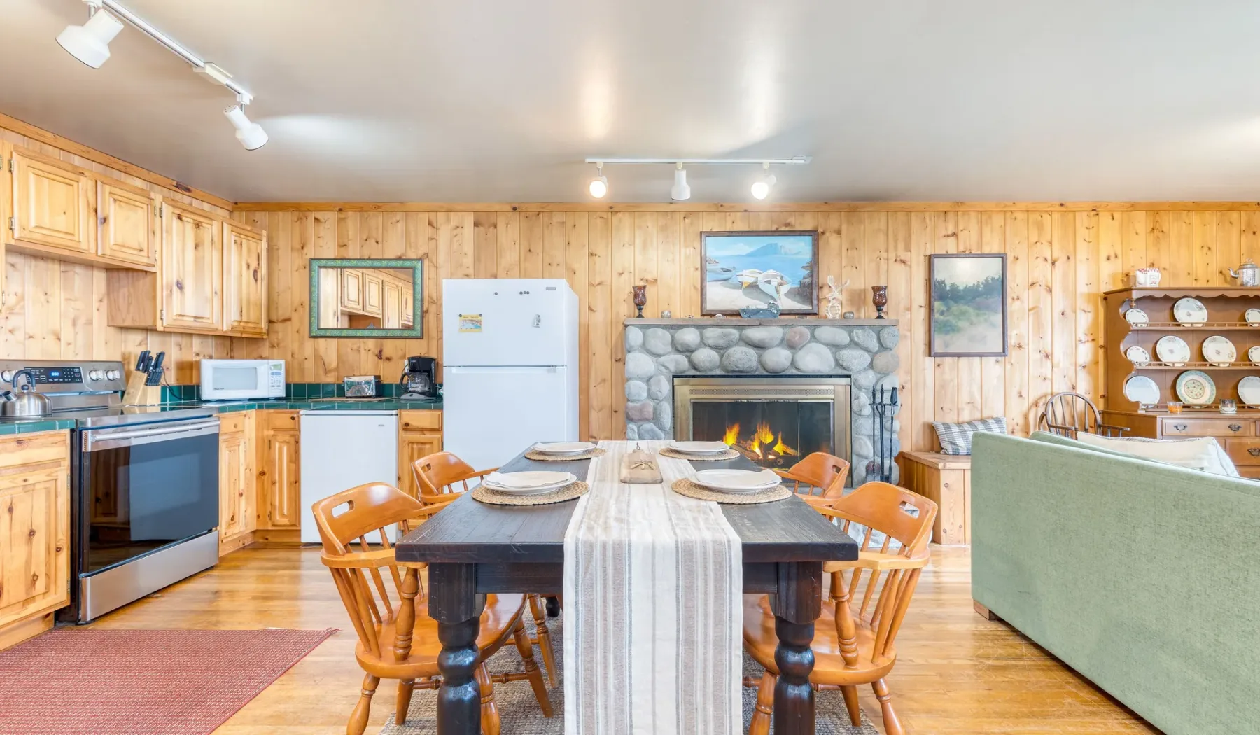 Una cocina y comedor revestidos de madera con una chimenea de piedra.