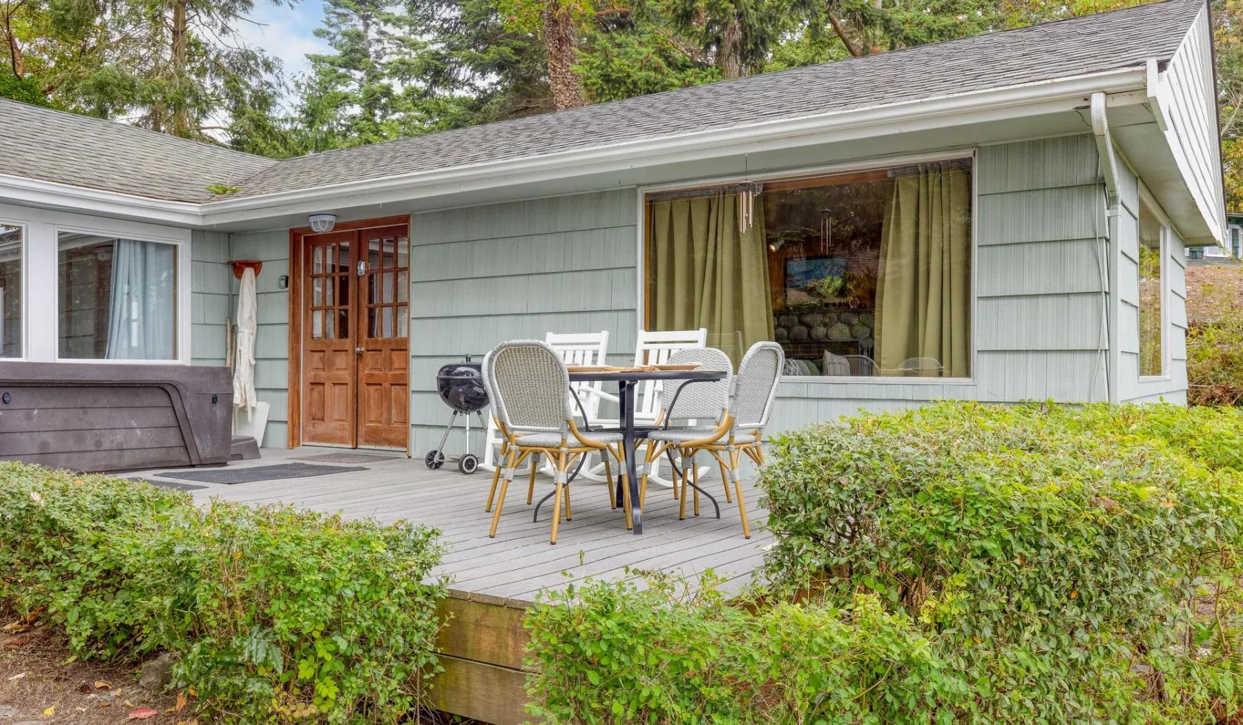 Exterior de una casa con una terraza de madera y muebles de comedor al aire libre.