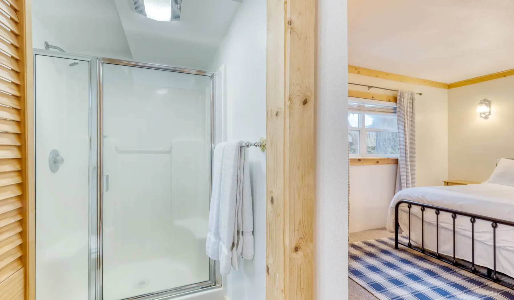 Un baño con ducha de vidrio junto a un dormitorio con una cama.