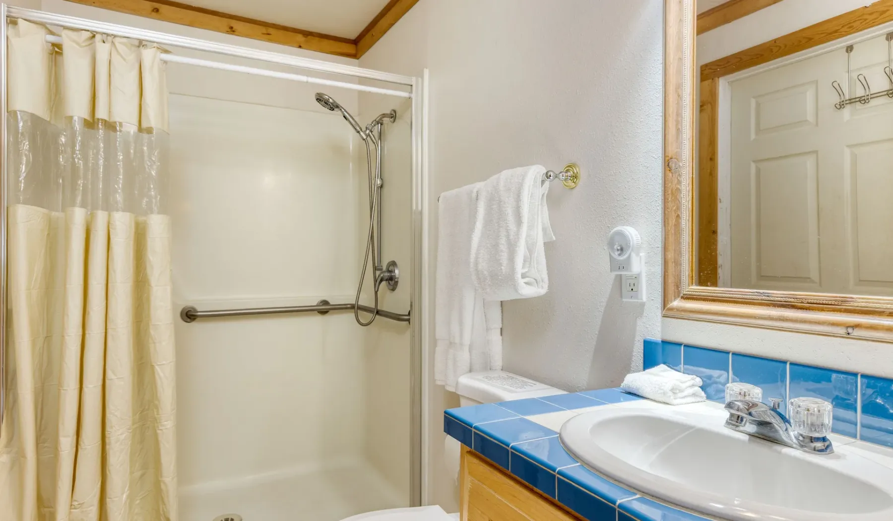 Un baño con ducha, cortina y encimera azul junto al lavabo.