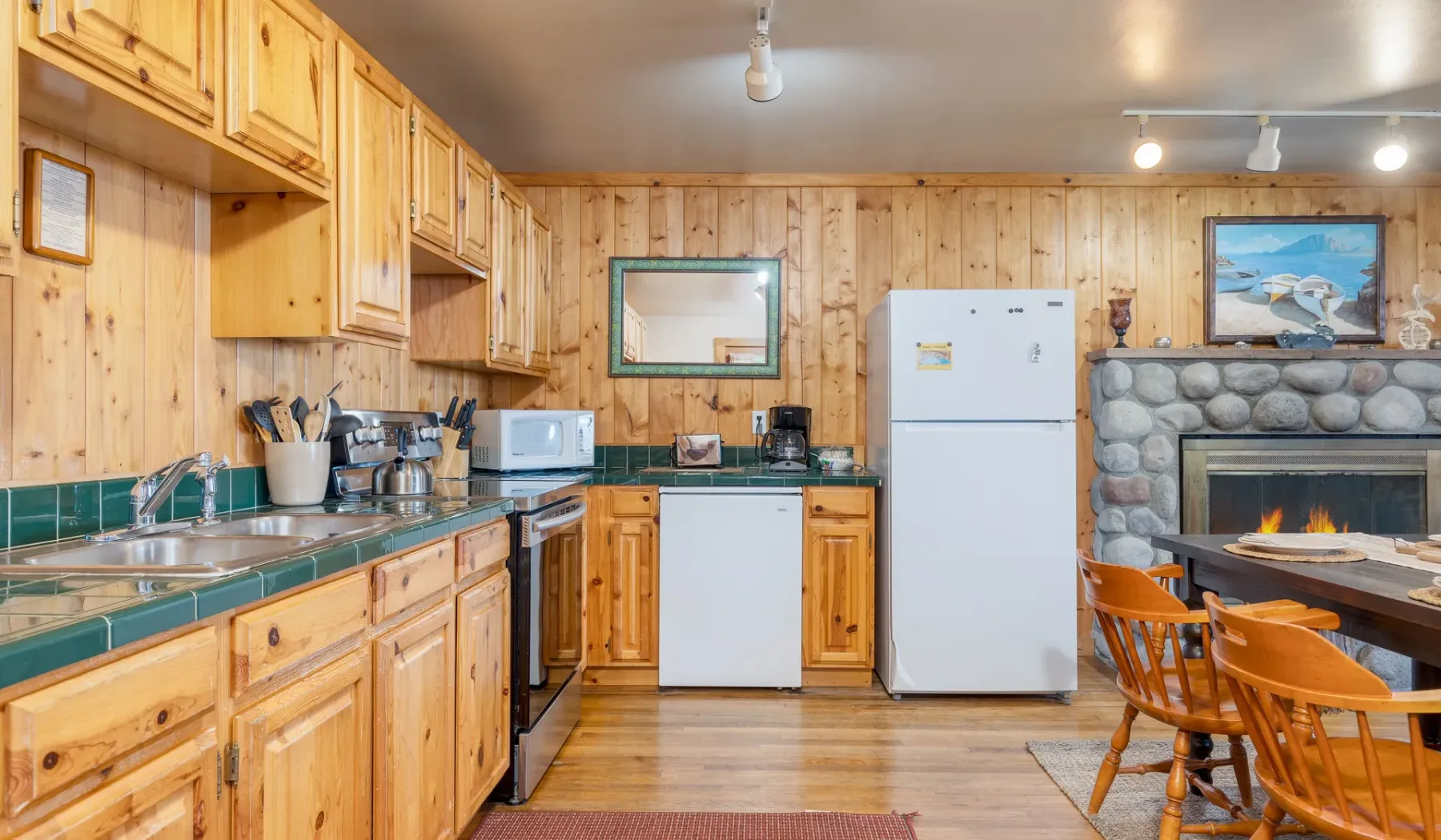 Cocina y comedor con paredes de madera y una chimenea de piedra.