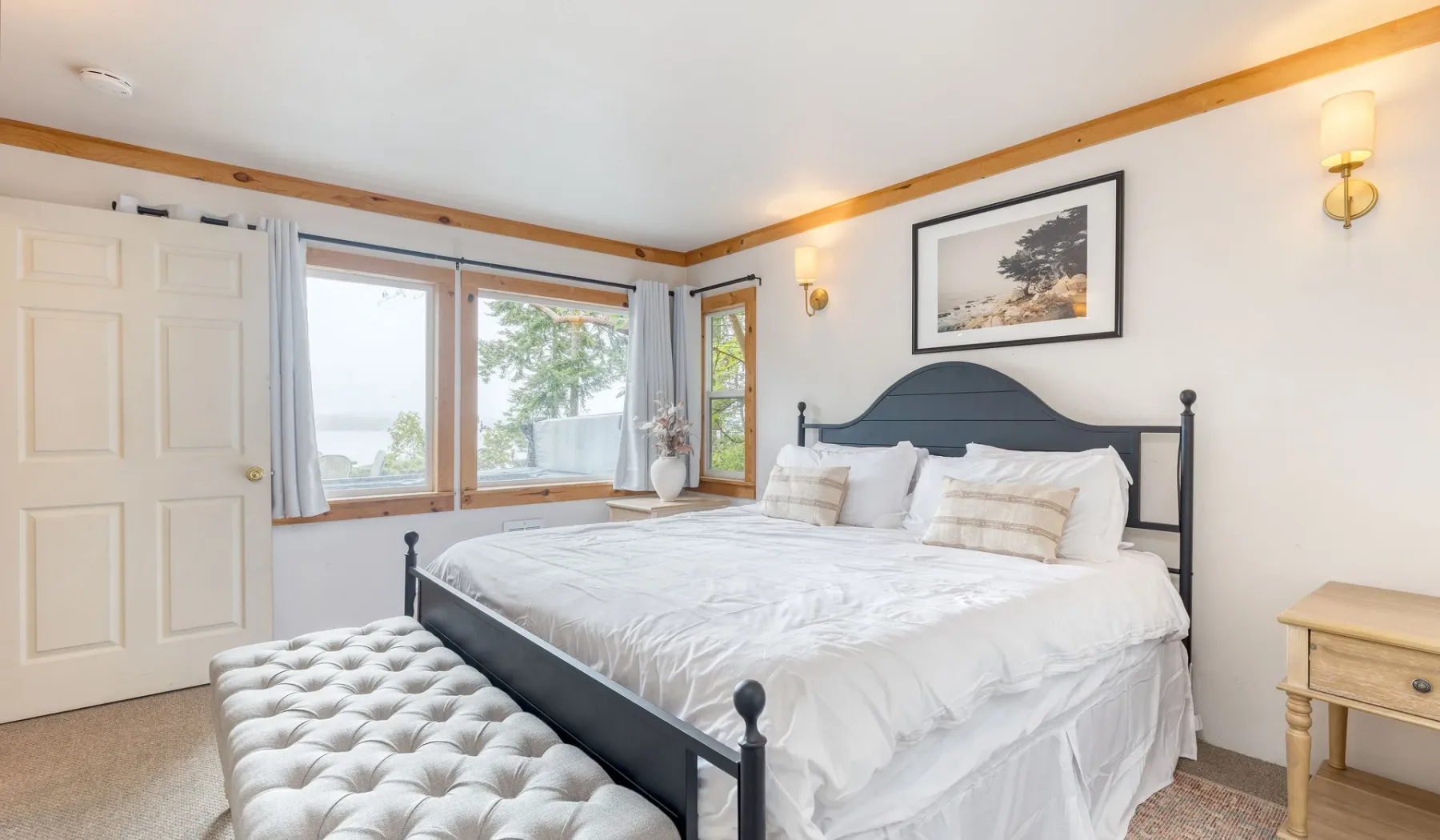 Un dormitorio luminoso con una cama grande, ventanas y un banco acolchado.