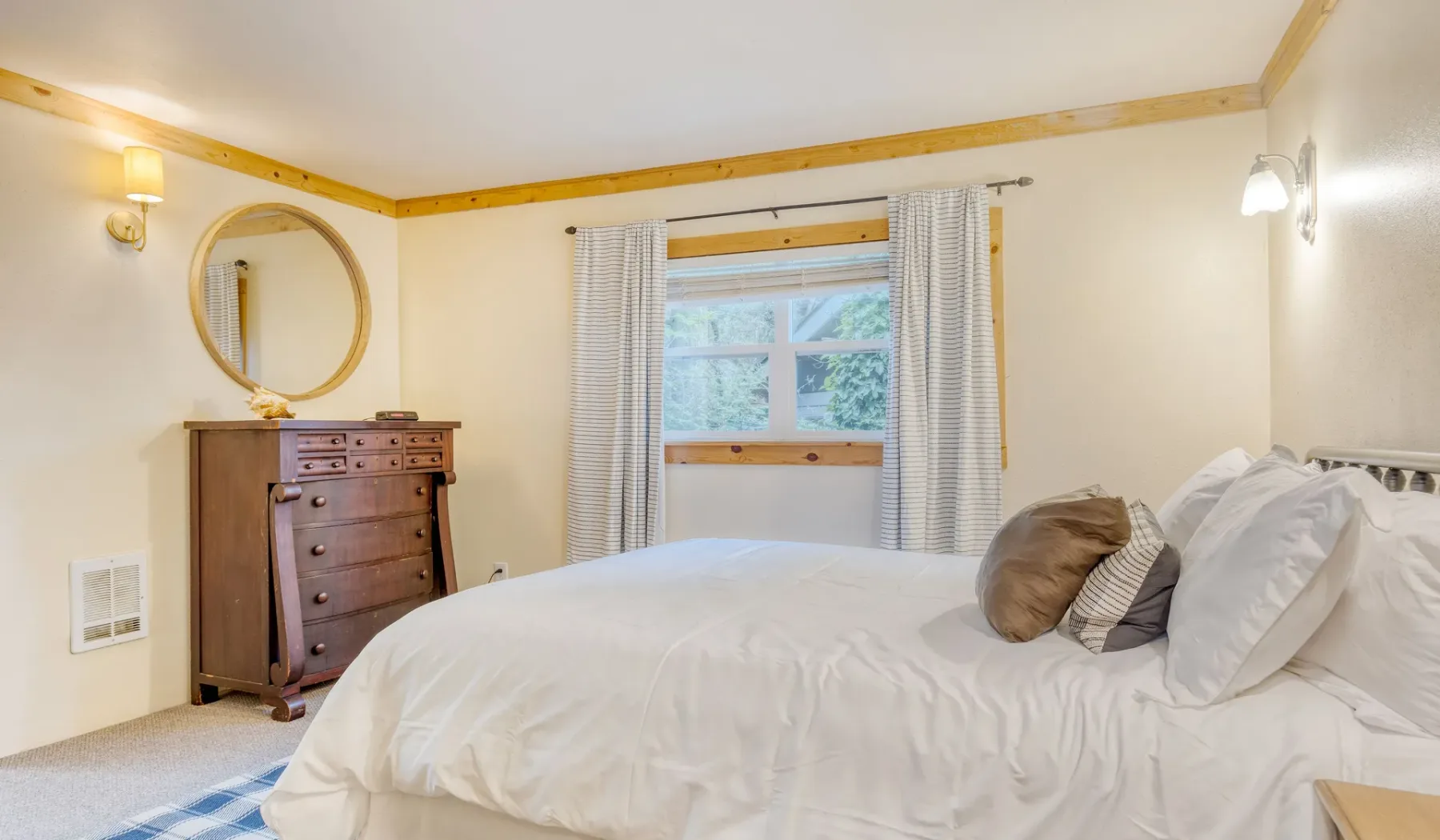 Un dormitorio con una cama junto a una ventana y una cómoda de madera.