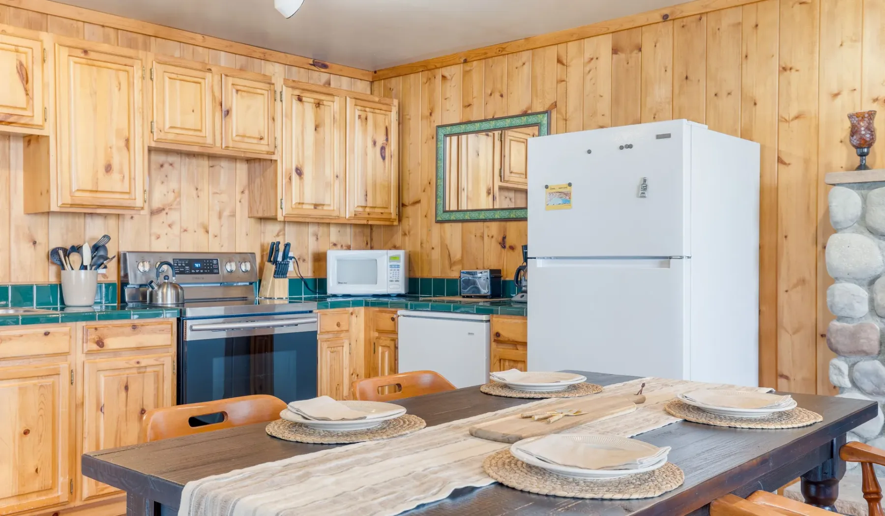Una cocina revestida de madera, con armarios, un refrigerador y una mesa de comedor.