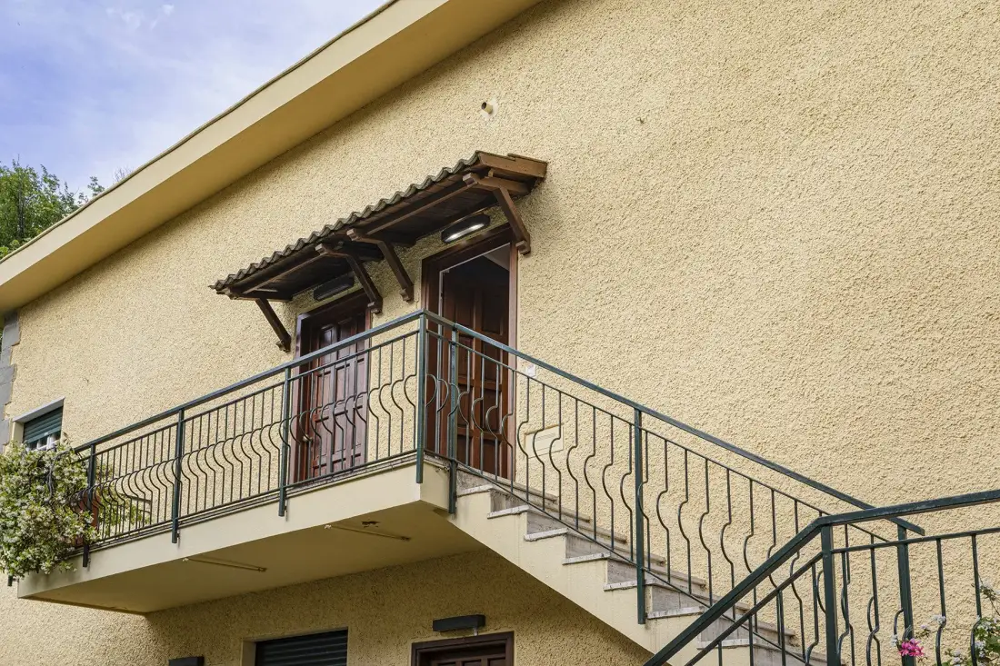 Exterior balcony with metal railings in front of a stucco wall.
