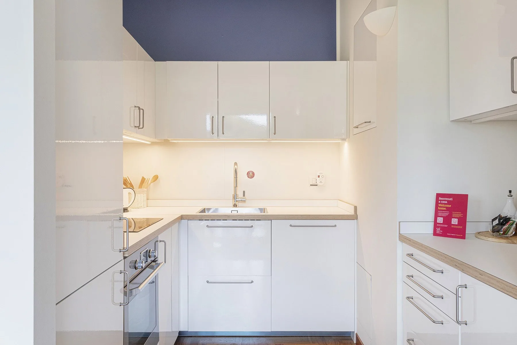A bright white kitchen with built-in cabinets, a countertop, and a sink.