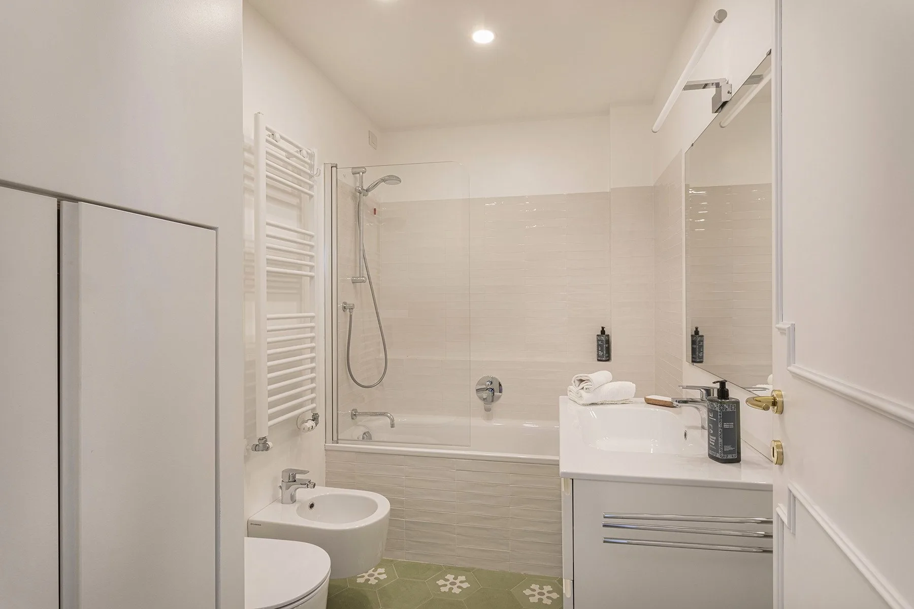 A bright bathroom with a bathtub, shower, and sink.