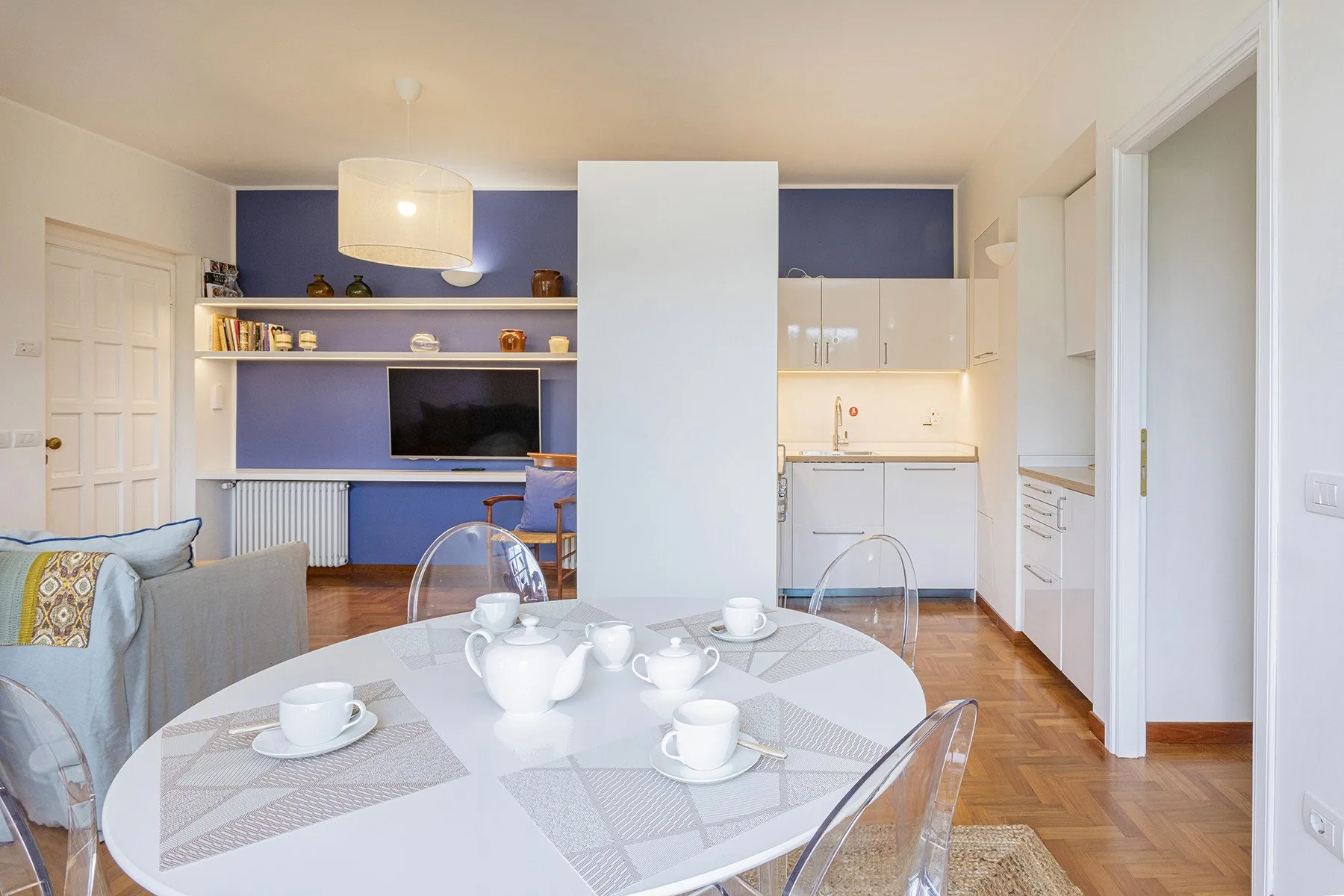 A bright dining area opens onto a compact kitchen, with a set table in the foreground.