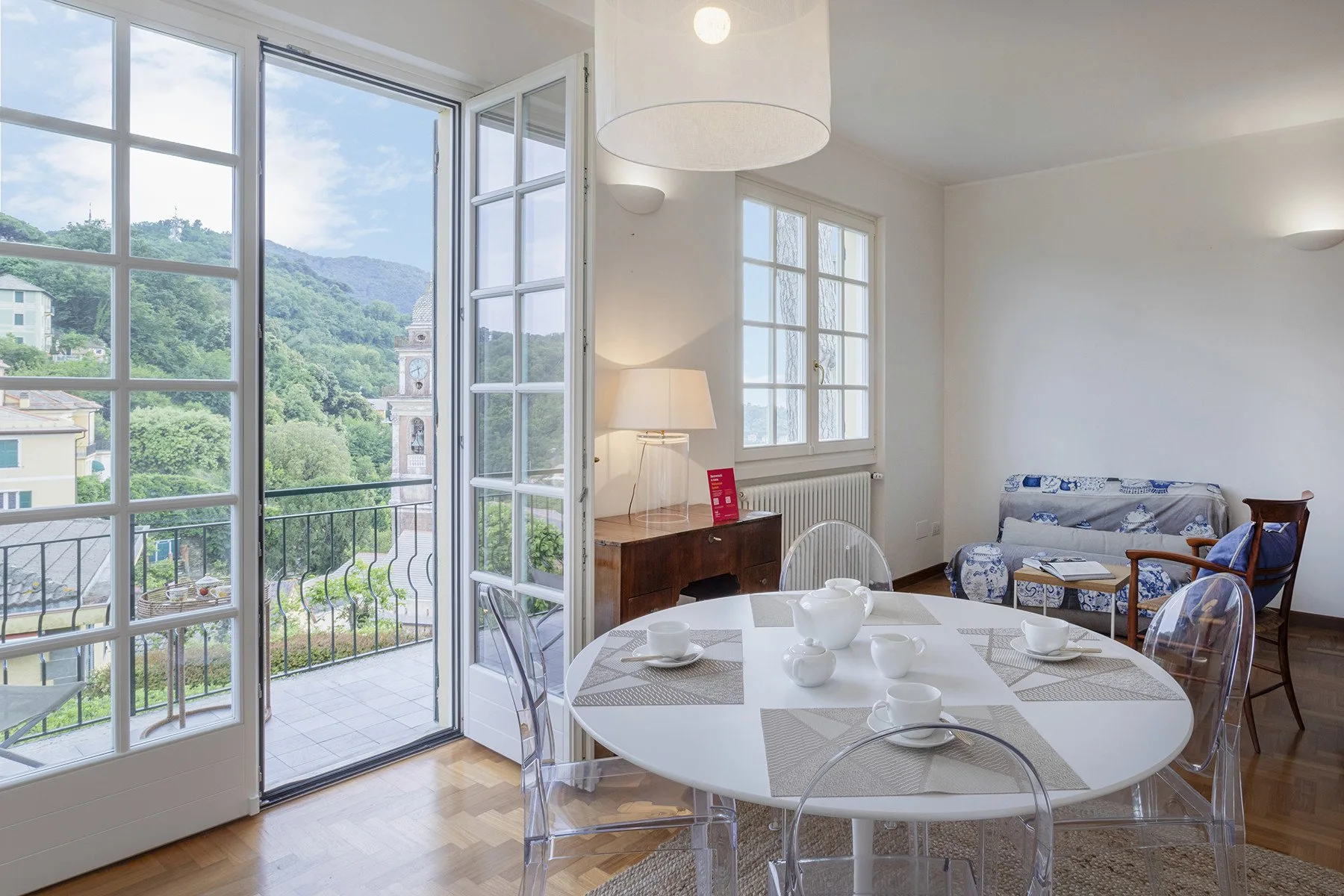 A bright dining and sitting room opens onto a balcony through large windows.